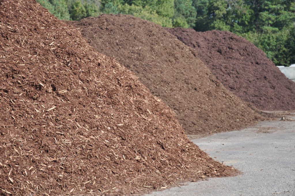 Large piles of mulch on the side of the road